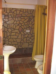 a bathroom with a stone shower curtain and a toilet at Hosteria La Morada in Tilcara