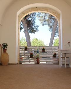 un arco con una valla, una mesa y un árbol en B&B Masseria Donna Carlotta, en Serrano