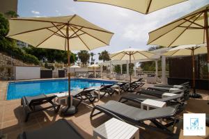 a pool with lounge chairs and umbrellas next to a pool at Apartamentos Seven Village in Benalmádena