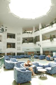 a woman sitting on couches in a large building at El Mouradi Skanes in Monastir