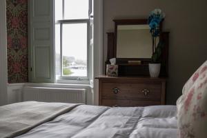 een slaapkamer met een bed, een spiegel en een dressoir bij Pennygate Lodge in Craignure