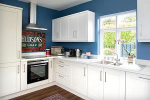 a kitchen with white cabinets and a blue wall at The Dolls House in Wexford