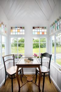 una mesa y sillas en una habitación con ventanas en The Dolls House en Wexford