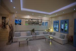 ein großes Wohnzimmer mit weißen Sofas und einem Tisch in der Unterkunft Fragiskos Hotel in Matala