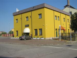 a yellow building with a car parked in front of it at Hostiliae Ciminiera Hotel in Ostiglia