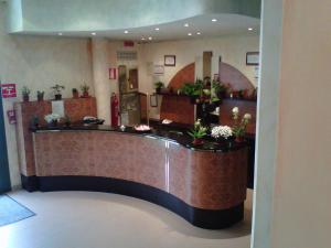 a lobby with a reception desk with potted plants at Hostiliae Ciminiera Hotel in Ostiglia