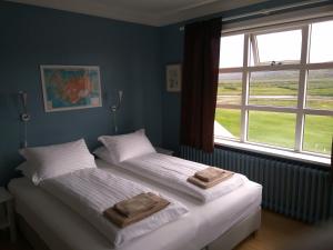 Dos camas en un dormitorio con dos toallas. en Hótel Laugarhóll with natural hot spring, en Hólmavík