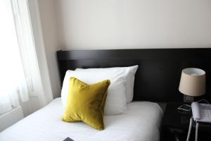 ロンドンにあるブルームズベリー パレス ホテルのベッド(黄色の枕と白の枕付)