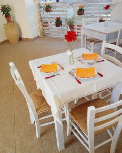 una mesa blanca con servilletas rojas y flores rojas. en B&B Masseria Donna Carlotta, en Serrano