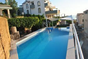 a large blue swimming pool next to a house at Apartments Marić in Primošten