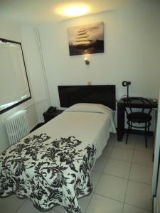 a bedroom with a black and white bed and a chair at Hotel Peralba in Aixovall