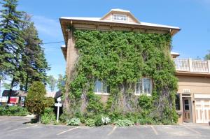 a building covered in ivy in a parking lot at Auberge La Seigneurie in Matane