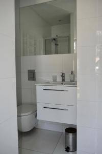 a white bathroom with a sink and a toilet at VIU Garden & Sun in Sopot