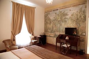 Schlafzimmer mit einem Bett, einem Schreibtisch und einem TV in der Unterkunft Grand Hôtel des Ambassadeurs in Menton