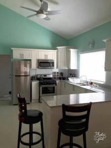 una cocina con armarios blancos y 2 taburetes en Caymanas Estate beautiful three bedroom house, en Spanish Town