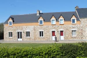 un gran edificio de ladrillo con puertas y ventanas rojas en Les Ecuries, en Saint-Maurice-en-Cotentin
