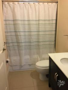 a bathroom with a toilet and a shower curtain at Caymanas Estate beautiful three bedroom house in Spanish Town