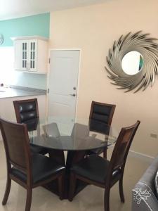 a dining room with a glass table and chairs at Caymanas Estate beautiful three bedroom house in Spanish Town