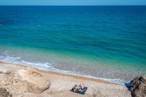 two people sitting on a beach next to the ocean at Hotel RH Vinarós Aura in Vinarós
