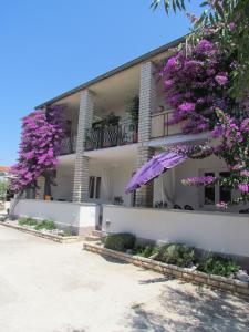 a building with purple flowering trees in front of it at Apartments Pipi in Pakoštane