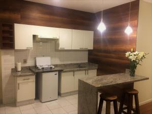 a kitchen with white cabinets and a counter with stools at Departamento De Lujo in Cochabamba