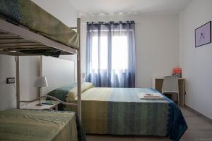 sypialnia z dwoma łóżkami piętrowymi i oknem w obiekcie B&B Agata e gli altri w mieście Tortolì