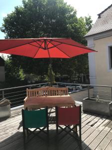 a wooden table with a red umbrella on a deck at Kaiserslautern Apartment in Kaiserslautern