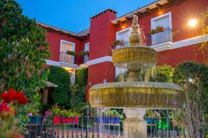 a fountain in front of a red house at Hotel Romerito in Málaga