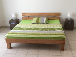 łóżko z zieloną kołdrą i 2 stolikami nocnymi w obiekcie Boardinghouse Casita Amann w mieście Friedrichshafen