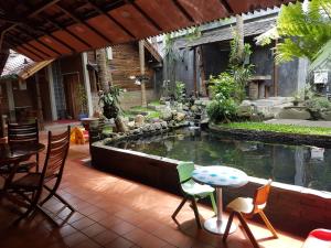 un patio con un estanque con sillas y una mesa en Peye Guesthouse en Malang