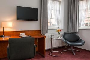 Habitación de hotel con escritorio, silla y TV. en Historik Hotel Garni Christinenhof en Hameln