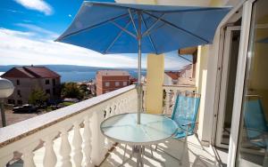 a glass table and a blue umbrella on a balcony at Apartment Crikvenica, Vinodol 3 in Crikvenica