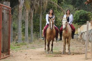 zwei Frauen reiten auf Pferden auf einer unbefestigten Straße in der Unterkunft Big Valley Hotel Fazenda in Serra Negra