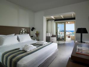 a bedroom with a large bed and a living room at Kakkos Beach Hotel - Adults Only in Ierápetra