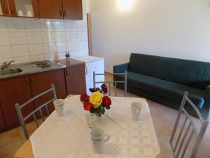 a kitchen and a table with a vase of flowers on it at Apartment Lopar 11 in Lopar