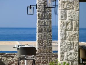 Kakkos Beach Hotel - Adults Only في إرابيترا: طاولة وكرسي للجلوس بجوار عامود حجري
