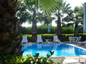 a swimming pool with chairs and palm trees at Apartment Marina di Ascea 2 in Castellammare di Velia