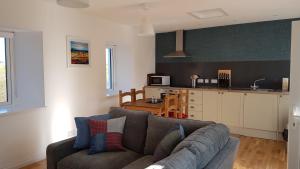 a living room with a couch and a kitchen at Cottages Lyndale Farm in Flashader