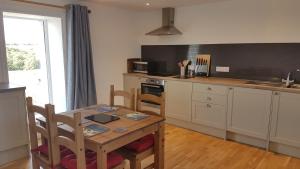 a kitchen with a wooden table and a table and chairs at Cottages Lyndale Farm in Flashader +24 photos