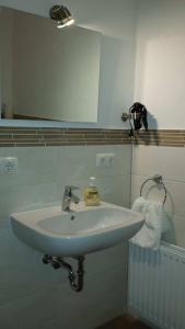 lavabo blanco en el baño con espejo en Gästehaus Beckord en Hodenhagen