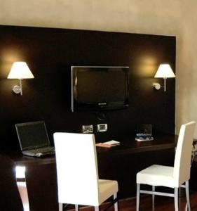 Habitación con escritorio, ordenador portátil y 2 sillas blancas. en Cremona Palace Hotel, en Costa Santʼ Abramo