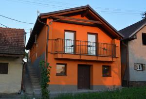 an orange house with a balcony and stairs at Ubytovani U Ruzenky in Velké Bílovice