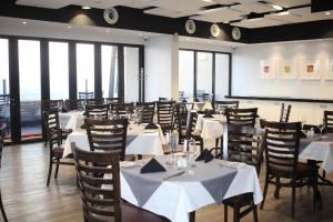a dining room with white tables and chairs and windows at Tower Bliss Apartment in Gaborone