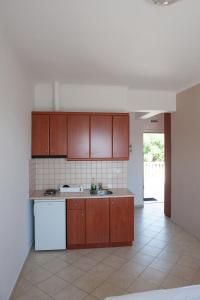 La cuisine est équipée de placards bruns et d'un réfrigérateur blanc. dans l'établissement Nikolaou Thomas House, à Parga