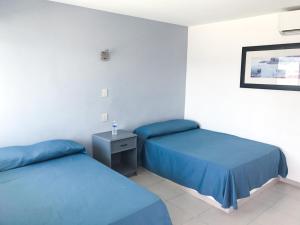 two beds in a room with blue sheets at Mona Inn in Mazatlán