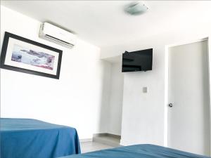 Habitación con cama y TV en la pared. en Mona Inn, en Mazatlán