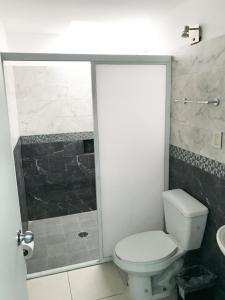 a bathroom with a white toilet and a shower at Mona Inn in Mazatlán