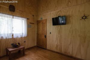 Habitación con puerta y TV en la pared en Cabañas Pilahue, en Las Trancas