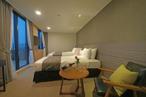 um quarto de hotel com duas camas e uma mesa em I-Jin Hotel em Jeju