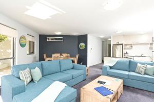 a living room with two blue couches and a table at Sevan Apartments Forster in Forster